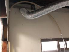 壁に穴をあけ排気ダクトを取り付けし、システムバス上部に温水配管を事前に仕込んでおきます。
